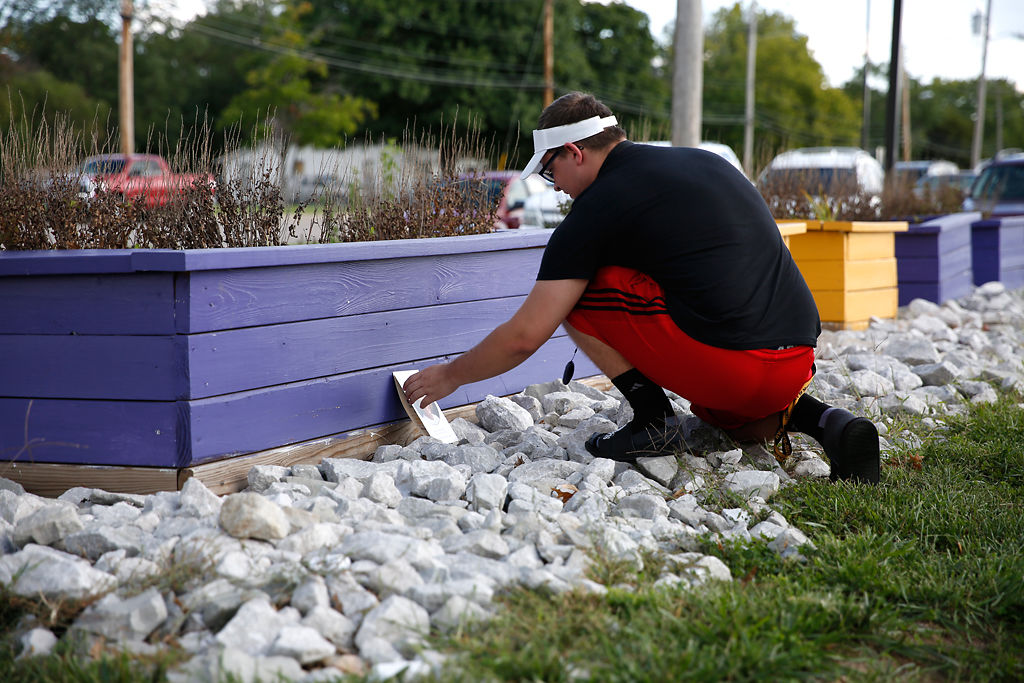 Hickman High School junior Dylan Shelton sets a photo of Janna Fick next to a garden box